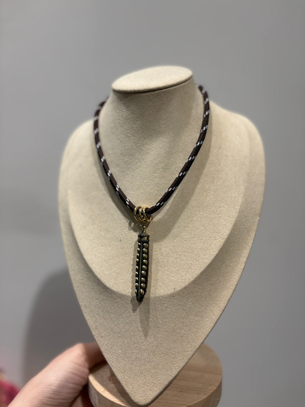 Collana con cordoncino intrecciato e pendente con borchie metalliche